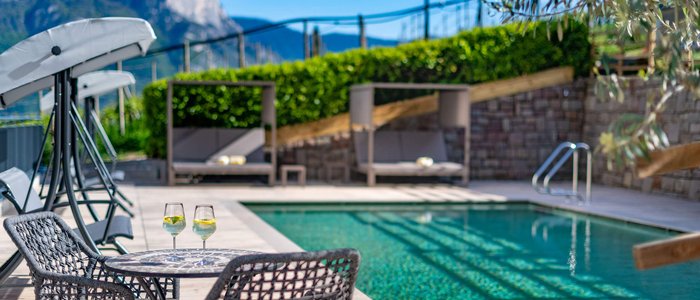 Poolterrasse mit zwei Drinks auf einem Tisch und Bergblick im Hintergrund