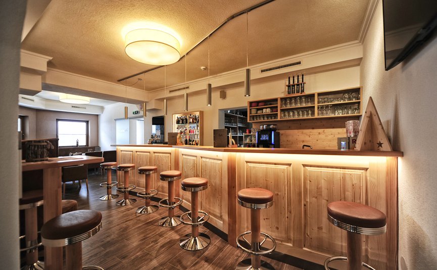 Bar met houten toonbank en krukken in warm verlichte ruimte