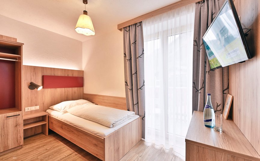 Haus Flexen © Mathies Wilhelm Robert jun. Kleines modernes Einzelzimmer mit Bett, TV und Fenster mit Vorhängen