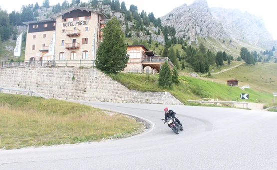 Motorradfahrer fährt auf kurviger Bergstraße am Hotel Pordoi