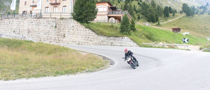 Motorcyclist riding on winding mountain road near Hotel Pordoi
