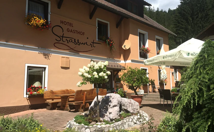 Exterior view of Hotel Gasthof Strasswirt with seating area and flower decorations