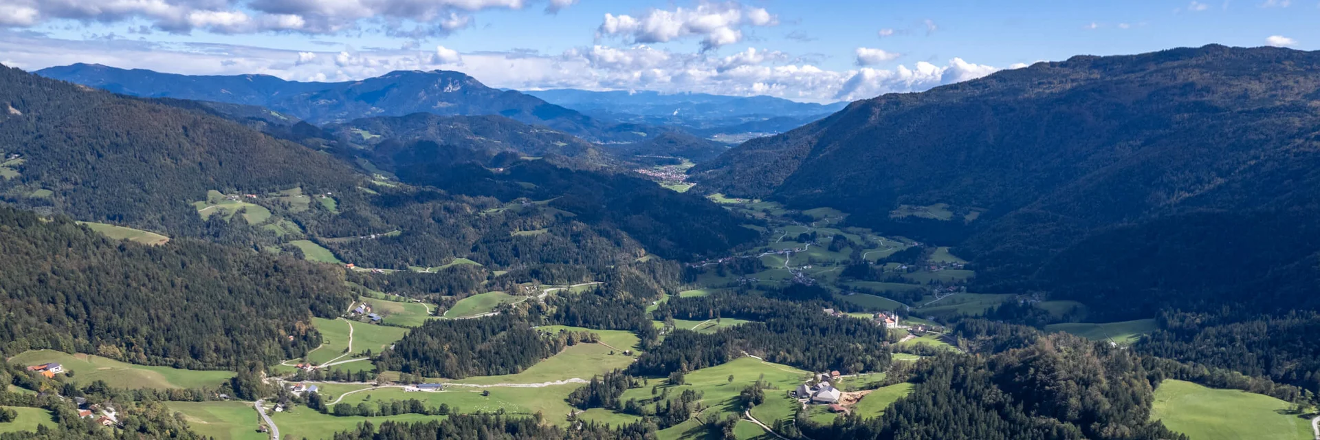 Savinja Tal © Igor Rosina Luftaufnahme eines grünen Bergtals mit verstreuten Häusern und bewaldeten Hängen