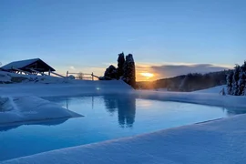 Babymoon im Hotel Rockenschaub Beheizter Außenpool im Schnee bei Sonnenuntergang