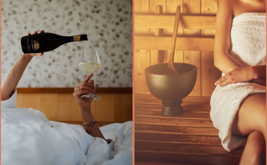 Person gießt Wein ins Glas im Bett, daneben sitzt jemand mit Handtuch in Sauna