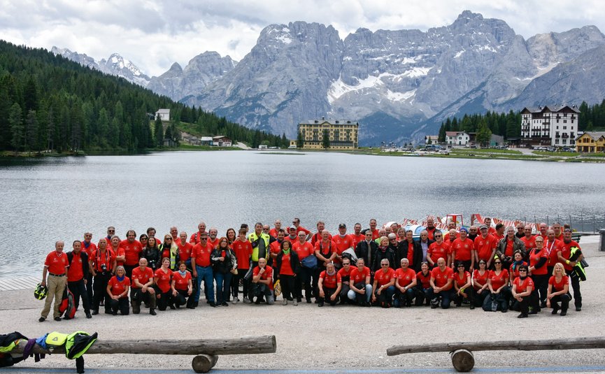 Albergo Panorama *** © Daniele Rodorigo Große Gruppe von Menschen in roten Shirts vor Bergsee und Alpenkulisse