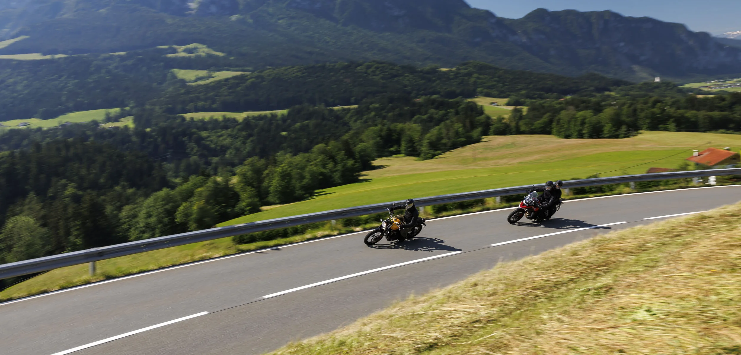 Duitsland © Jörg Künstle Twee motorrijders op kronkelende bergweg met bergen op de achtergrond