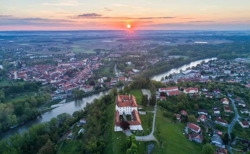 Wijnroute Karinthië-Styrië Luchtfoto van een stad met rivier en kasteel bij zonsondergang