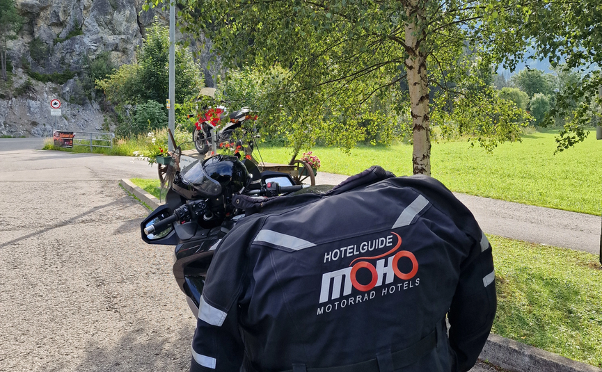 Motorrad mit MOHO Motorrad Hotels Jacke an einem sonnigen Rastplatz