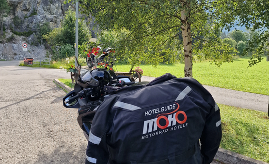 Motorrad mit MOHO Motorrad Hotels Jacke an einem sonnigen Rastplatz