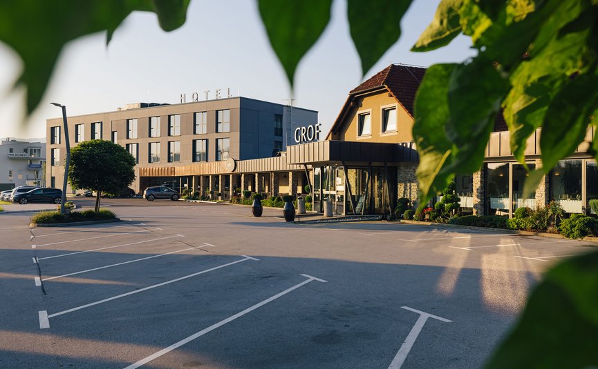 Hotelgebäude mit Parkplatz und Bäumen bei Tageslicht