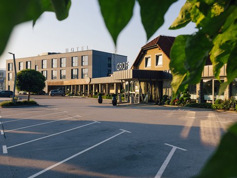 Hotelgebäude mit Parkplatz und Bäumen bei Tageslicht