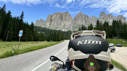 Motorradfahrer auf Bergstraße mit Nadelnadeln und Bergen im Hintergrund