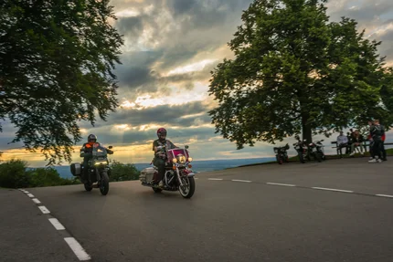 Twee motorrijders rijden bij zonsondergang een bocht voorbij.