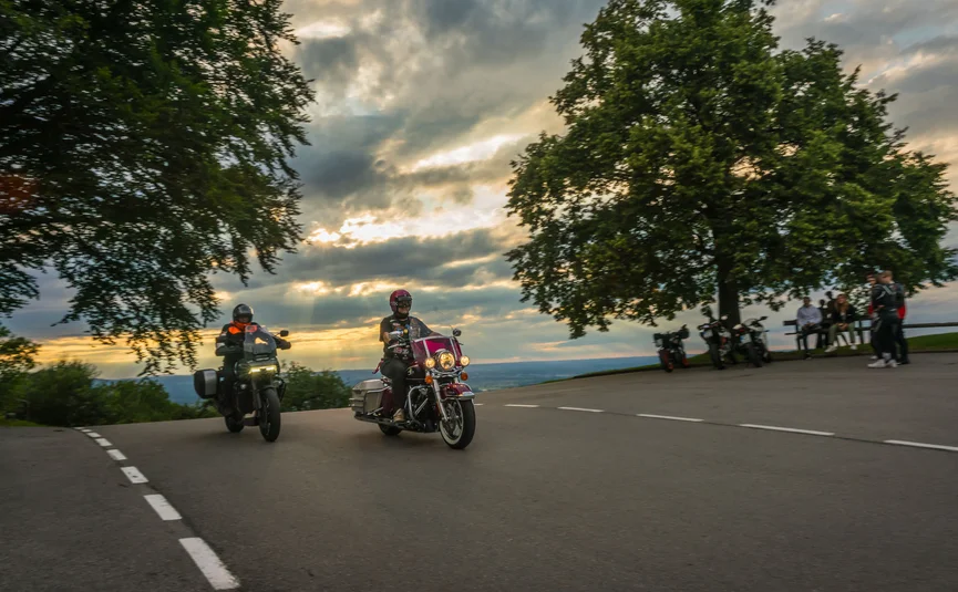 Motorbike holiday in Bavaria © Moppetfoto.de Two motorcyclists riding past a curve at sunset.