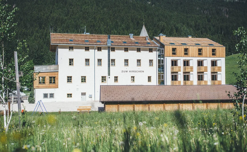 Gebouw Zum Hirschen in groene weiland met bos op de achtergrond
