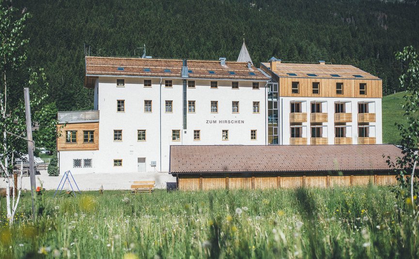 Gebouw Zum Hirschen in groene weiland met bos op de achtergrond