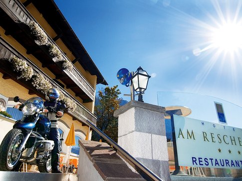 Hotel am Reschensee © The Dilitz Company GmbH Motorradfahrer vor Hotel Am Reschensee an sonnigem Tag