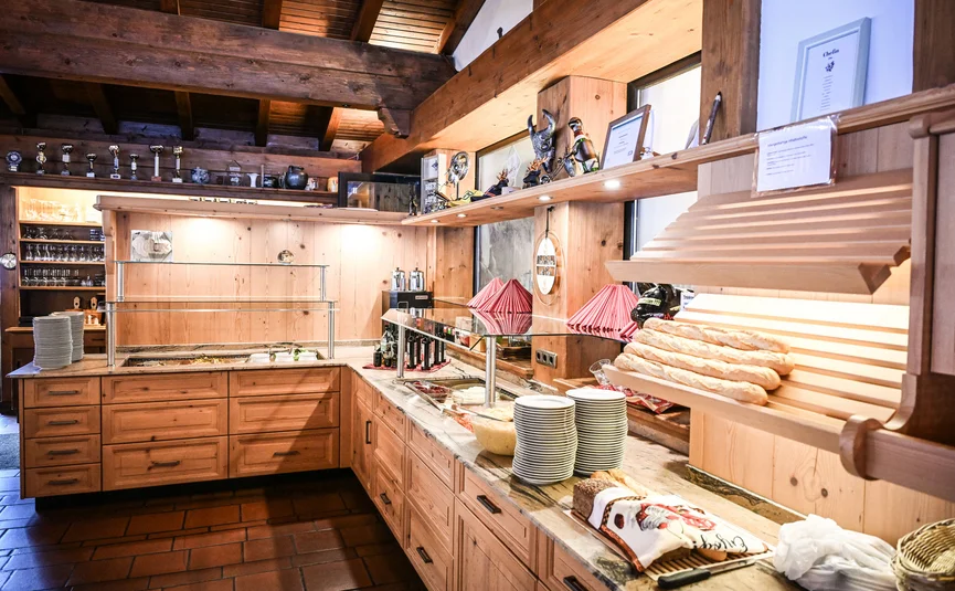 Rustic buffet counter with bread, plates, and glasses in cozy wooden interior