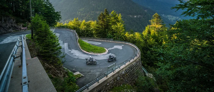 Sharp hairpin mountain road curve with two motorcycles