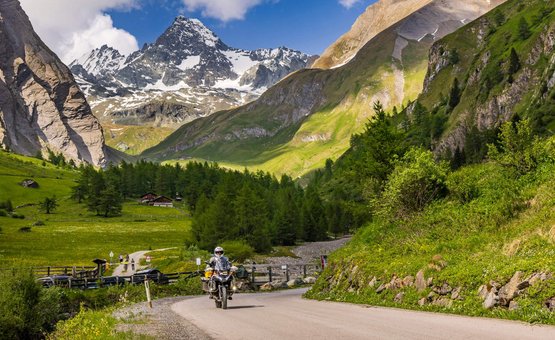 Motorradurlaub in Kärnten © Alexander Seger Motorradfahrer auf Bergstraße mit schneebedeckten Alpen und grüner Landschaft