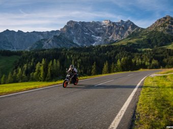 Motorradfahrer auf Bergstraße mit Bergen und Wald im Hintergrund