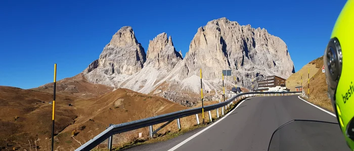 Bergweg met rotsachtige pieken en motorhelm onder heldere lucht