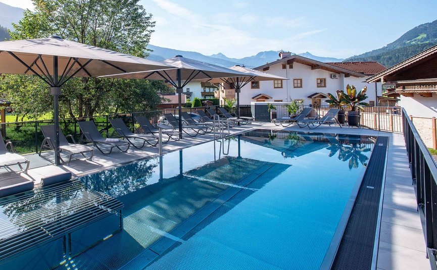 Moderner Außenpool mit Liegestühlen und Bergen im Hintergrund