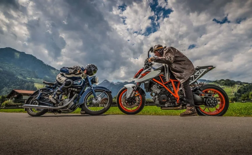 Twee motorrijders in racehouding op landweg met berglandschap op de achtergrond