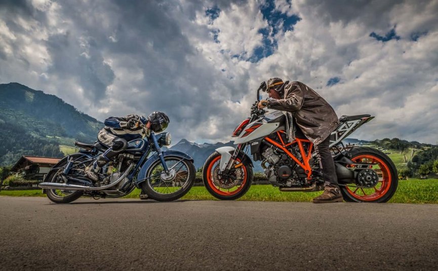 Sternfahrt Motorrad-Special ab € 628,- pro Person Zwei Motorradfahrer im Rennposition auf Landstraße mit Berglandschaft im Hintergrund