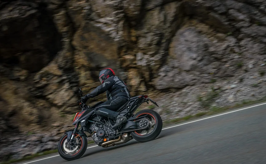 Motorcyclist in black gear riding on winding mountain road