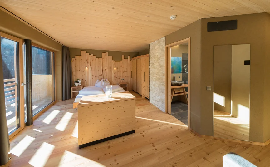 Bright bedroom with wooden furniture and large windows with curtains