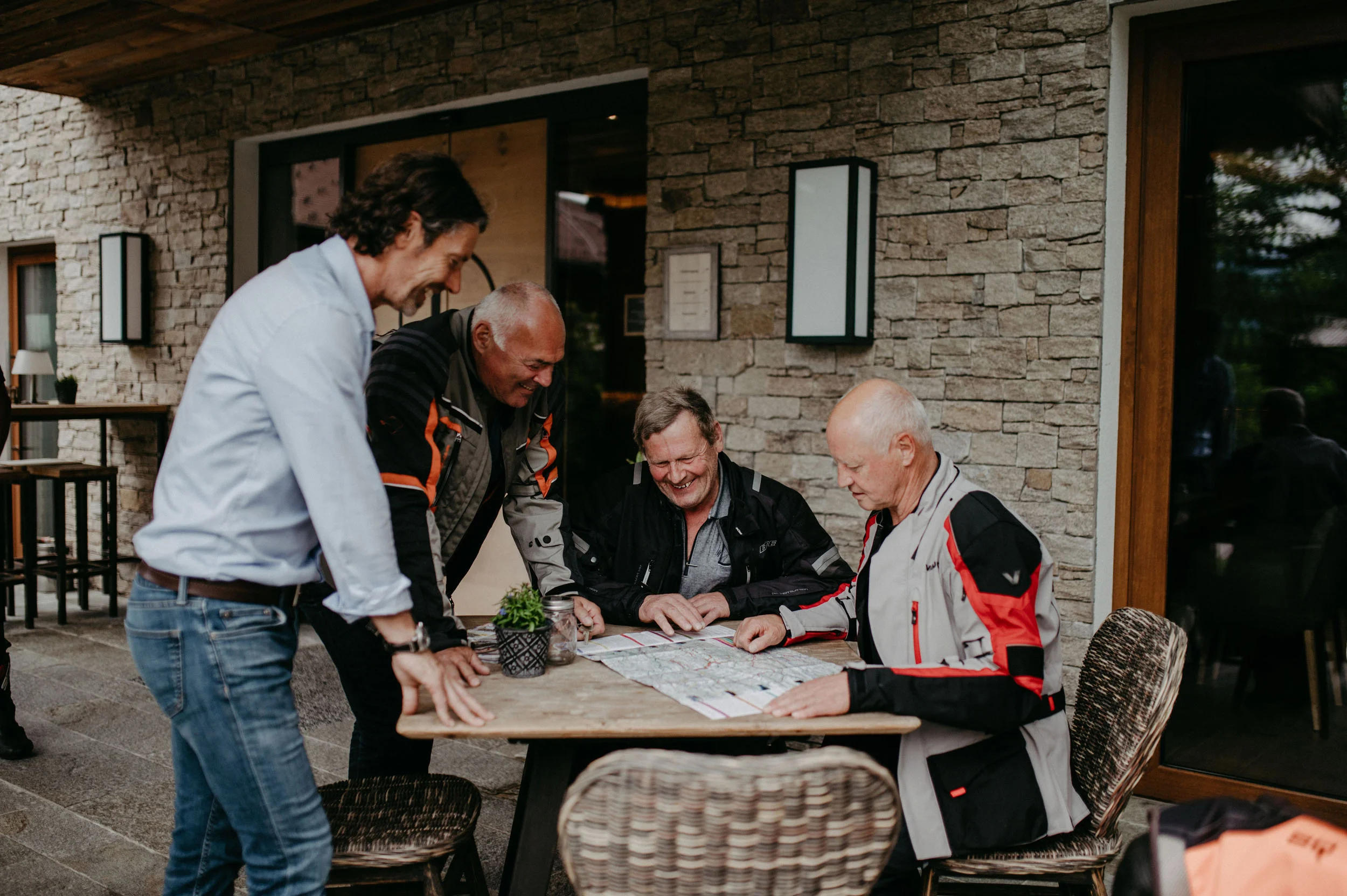 Tour planner Four men planning a trip using a map at an outdoor table
