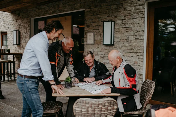 Tour planner Four men planning a trip using a map at an outdoor table