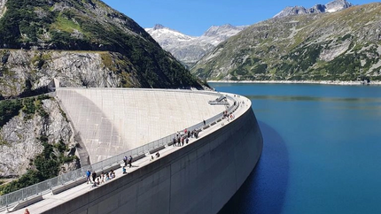 Menschen spazieren auf einem großen Staudamm in den Bergen