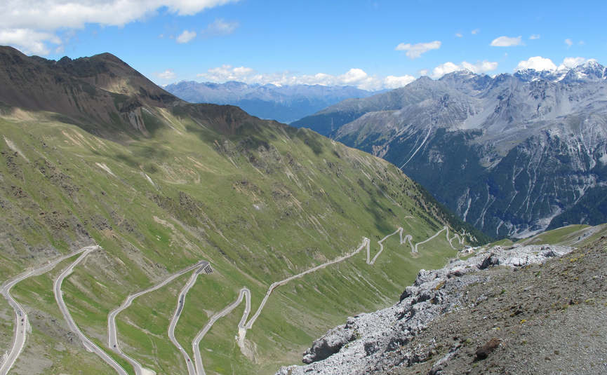 MoHo Schönauer Hof- Tour 12 Stilfserjoch Umbrail Winding mountain road in the Alps with clear sky and distant snowy peaks