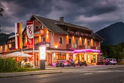 Beleuchtetes Hotel mit Motorrädern und Autos bei Abenddämmerung