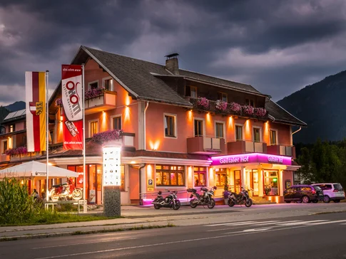 Beleuchtetes Hotel mit Motorrädern und Autos bei Abenddämmerung