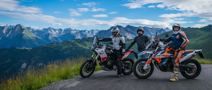 Three motorcyclists with helmets on mountain road with alpine scenery