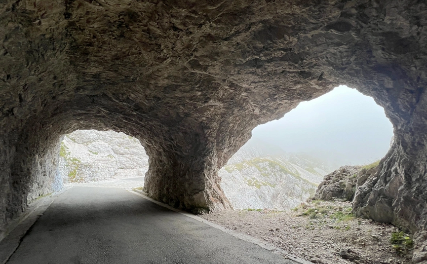 smalle bergtunnel met twee openingen en uitzicht op rotsachtig landschap