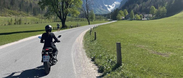 Motorradfahrer auf Straße mit Bergen und blauen Himmel im Hintergrund