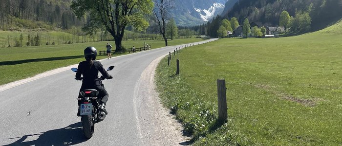 Motorrijder op weg met bergen en blauwe lucht op de achtergrond