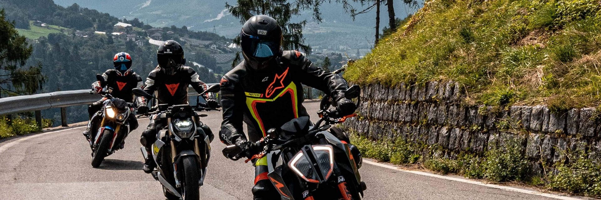 Val di Sole – Brenta Dolomiten – Gardasee © Andrea Acler Drei Motorräder fahren auf einer bergigen Straße mit Fahrern in Schutzkleidung