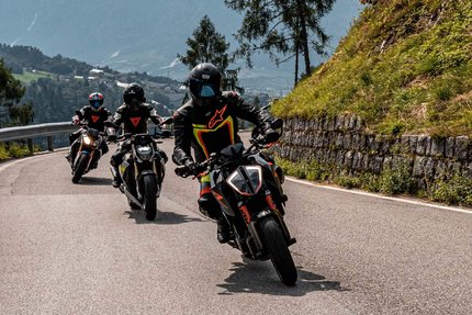 Drei Motorräder fahren auf einer bergigen Straße mit Fahrern in Schutzkleidung