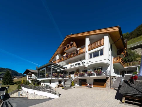Hotel Florian © Arik Oberrauch Hotel Florian mit Holzbalustraden und Blumen unter klarem blauem Himmel