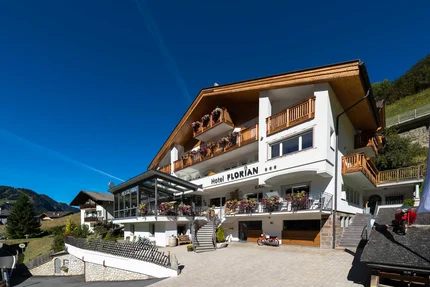 Hotel Florian with wooden balconies and flowers under clear blue sky
