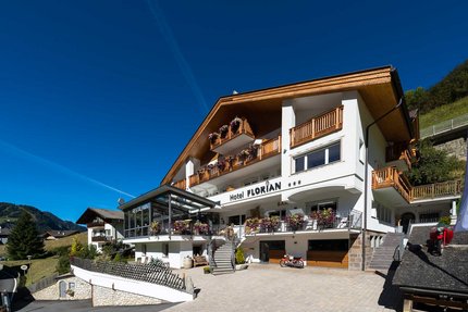 Hotel Florian © Arik Oberrauch Hotel Florian mit Holzbalustraden und Blumen unter klarem blauem Himmel