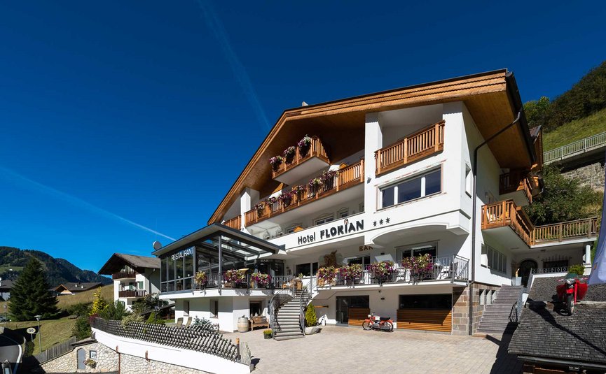 Hotel Florian ***S © Arik Oberrauch Hotel Florian mit Holzbalustraden und Blumen unter klarem blauem Himmel