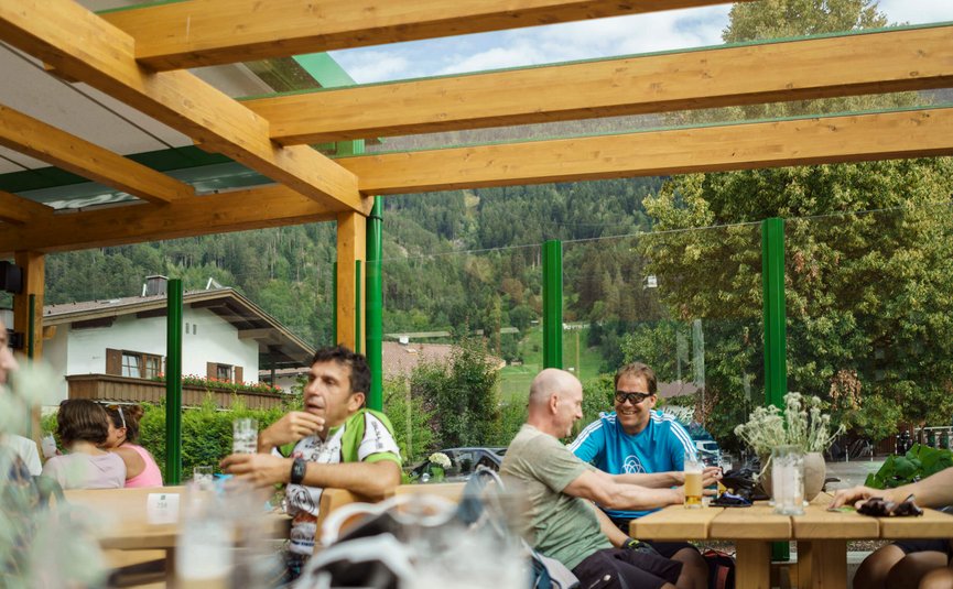 Hotel Jägerhof **** © Florian Scherl Menschen sitzen draußen an einem Holztisch mit Getränken und Bergblick