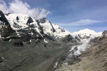 Snow-covered mountains with melting glacier under blue sky